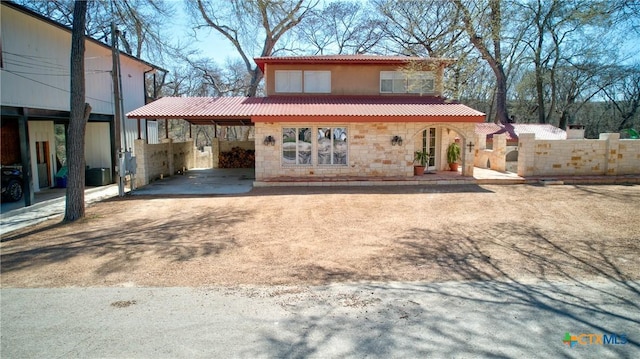 view of front of home with stone siding, a carport, and a tile roof