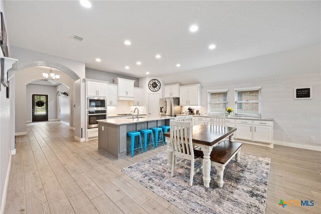 dining space with light wood-type flooring, baseboards, visible vents, arched walkways, and recessed lighting