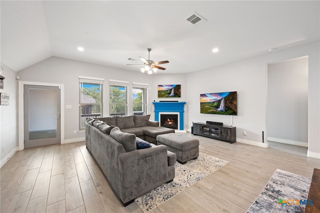 living area featuring a ceiling fan, a warm lit fireplace, light wood-type flooring, visible vents, and recessed lighting
