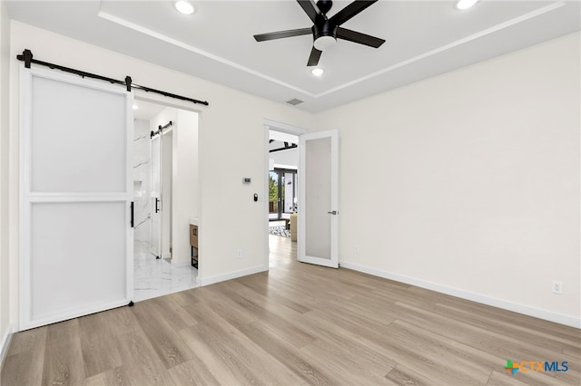 2637 Campestres, Spring Branch, TX 78070 - unfurnished bedroom featuring a barn door, recessed lighting, light wood finished floors, baseboards, and a tray ceiling