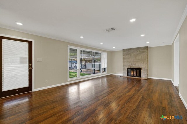 unfurnished living room with ornamental molding, a stone fireplace, and dark hardwood / wood-style flooring