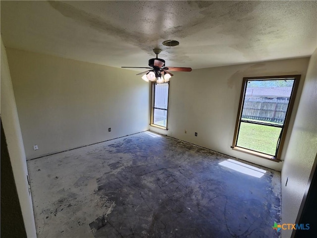 empty room with ceiling fan, concrete floors, and a textured ceiling