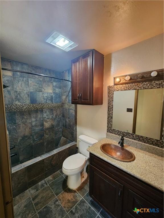 bathroom featuring vanity, toilet, and a tile shower