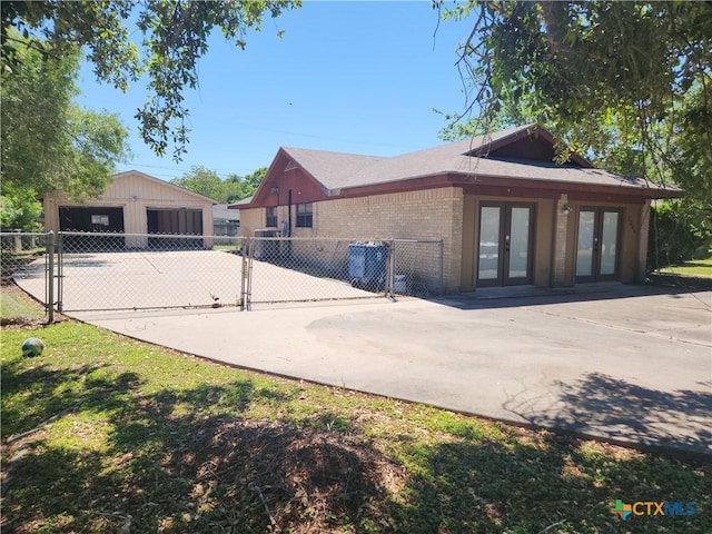 rear view of house with a garage, an outdoor structure, and french doors