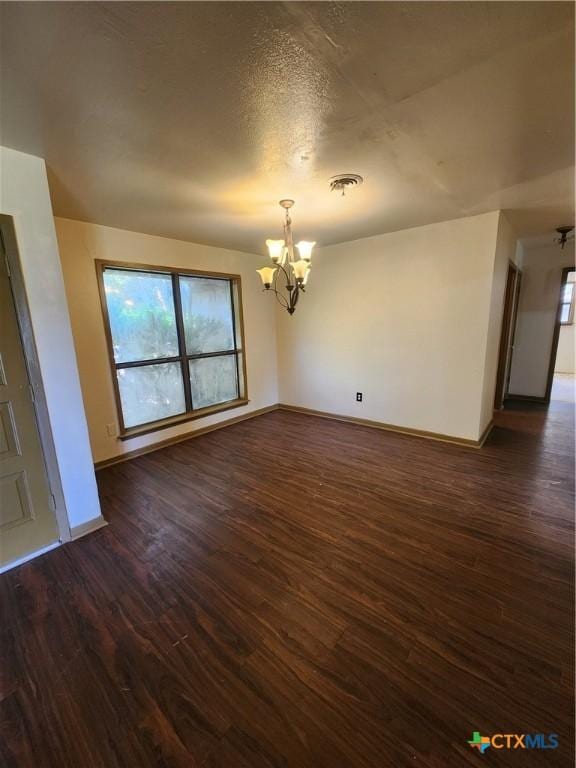 unfurnished room featuring dark wood-type flooring and a chandelier