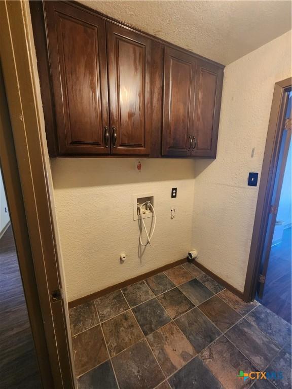 washroom featuring gas dryer hookup, cabinets, hookup for a washing machine, and a textured ceiling