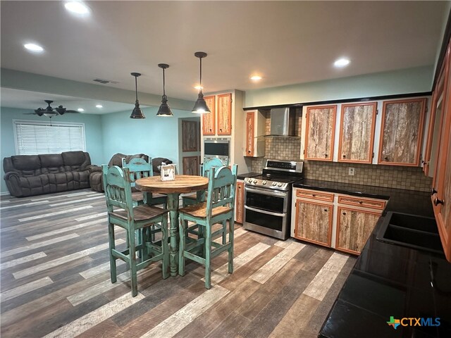 kitchen with stainless steel electric range, hanging light fixtures, decorative backsplash, dark wood-type flooring, and wall chimney exhaust hood