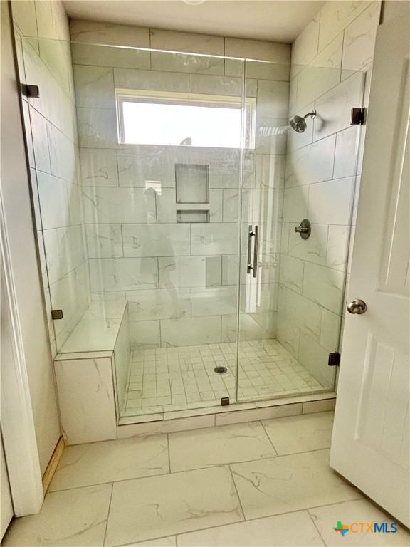 bathroom with a stall shower and marble finish floor
