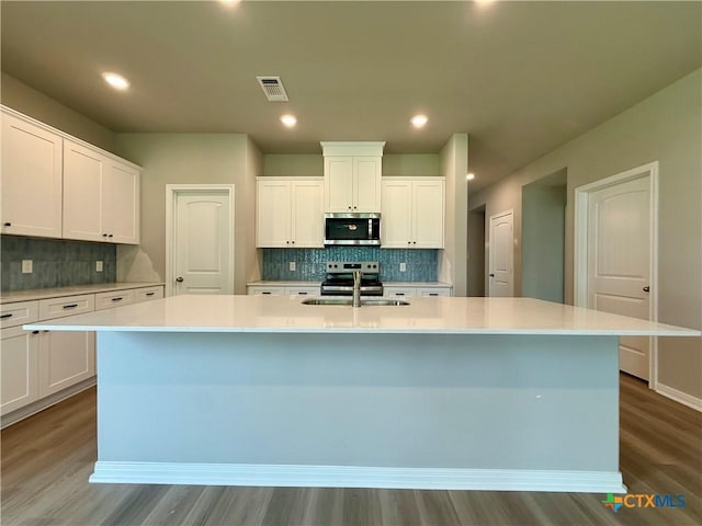 kitchen featuring wood finished floors, stainless steel microwave, visible vents, and a sink