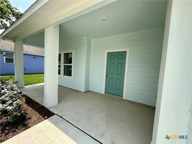 view of exterior entry with a patio area