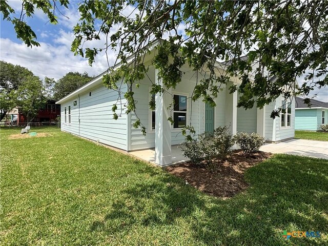 view of side of home with a lawn and a patio