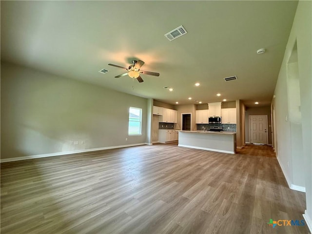 unfurnished living room with recessed lighting, visible vents, wood finished floors, and baseboards