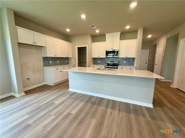 kitchen featuring baseboards, tasteful backsplash, appliances with stainless steel finishes, white cabinetry, and visible vents