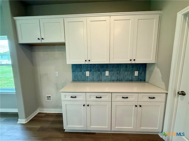 kitchen featuring white cabinetry, light countertops, decorative backsplash, and baseboards