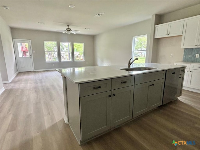 kitchen featuring white cabinetry, a kitchen island with sink, light wood finished floors, and a sink