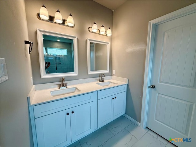full bath with double vanity, tiled shower, marble finish floor, and a sink