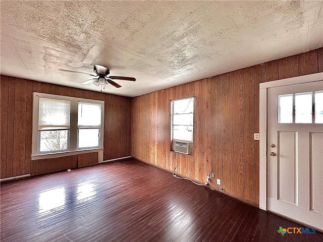 spare room featuring a healthy amount of sunlight, hardwood / wood-style flooring, a textured ceiling, and cooling unit