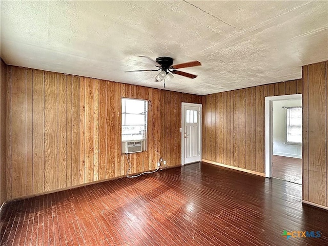 empty room with cooling unit, plenty of natural light, hardwood / wood-style floors, and ceiling fan