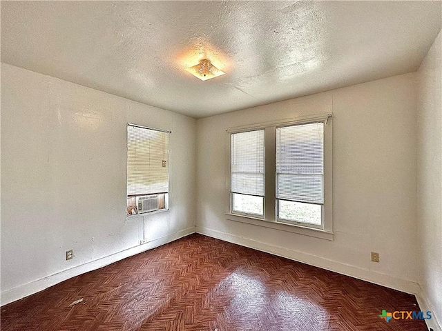 spare room with cooling unit, a textured ceiling, and baseboards