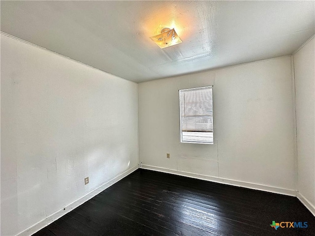 unfurnished room featuring baseboards and dark wood-type flooring