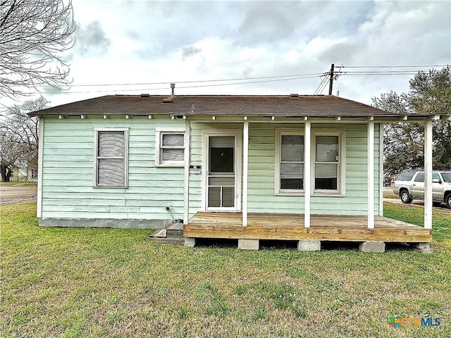 view of front of house with roof with shingles and a front lawn