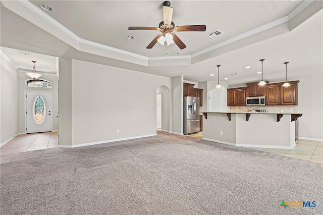519 Gianotti Ct, Temple, TX 76502 - unfurnished living room featuring a tray ceiling, light colored carpet, a ceiling fan, crown molding, and arched walkways