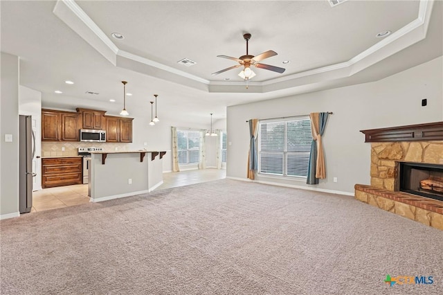 519 Gianotti Ct, Temple, TX 76502 - unfurnished living room featuring a tray ceiling, light colored carpet, ceiling fan, crown molding, and a stone fireplace