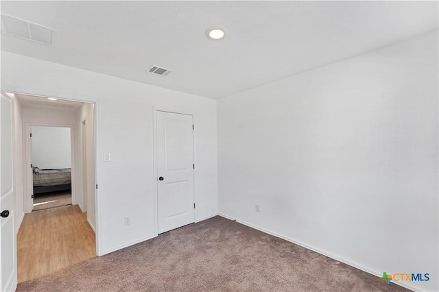 unfurnished bedroom featuring visible vents, light carpet, and baseboards