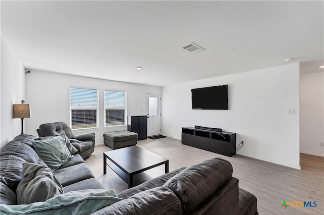 living room with light wood finished floors, visible vents, and baseboards