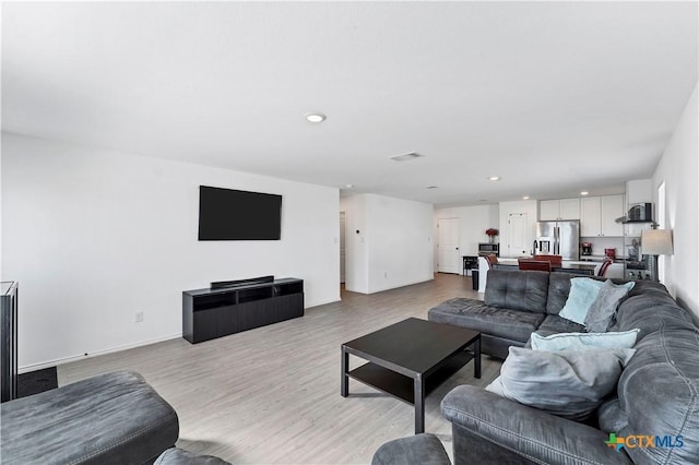 living room with recessed lighting, light wood-style floors, visible vents, and baseboards