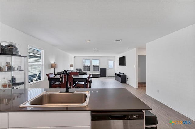 kitchen with a sink, dark countertops, dishwasher, and a wealth of natural light