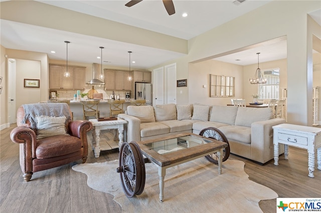 living room with ceiling fan with notable chandelier and wood-type flooring