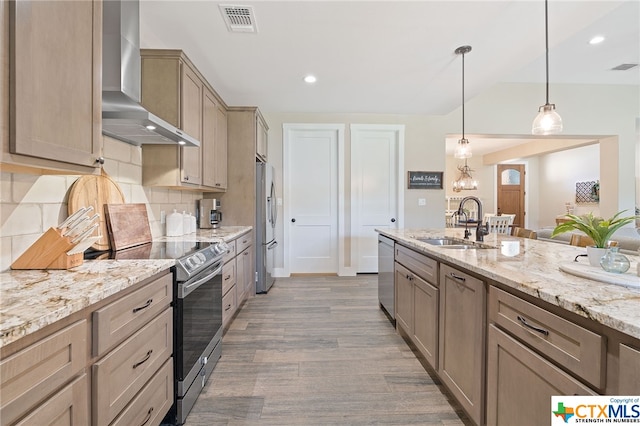 kitchen with stainless steel appliances, sink, backsplash, hanging light fixtures, and wall chimney range hood