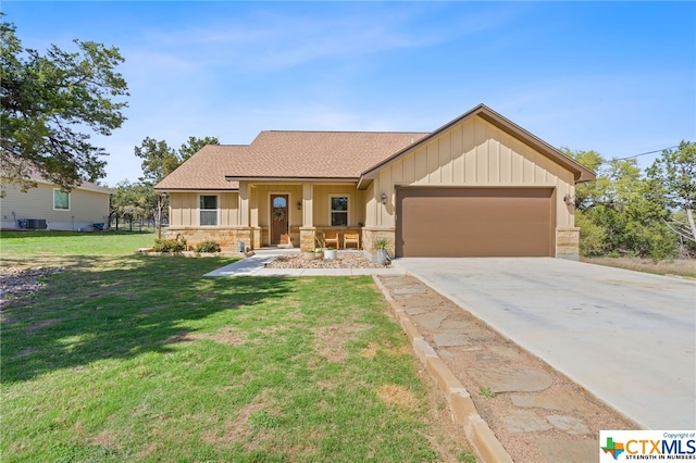 view of front of home with a garage, cooling unit, a front lawn, and covered porch