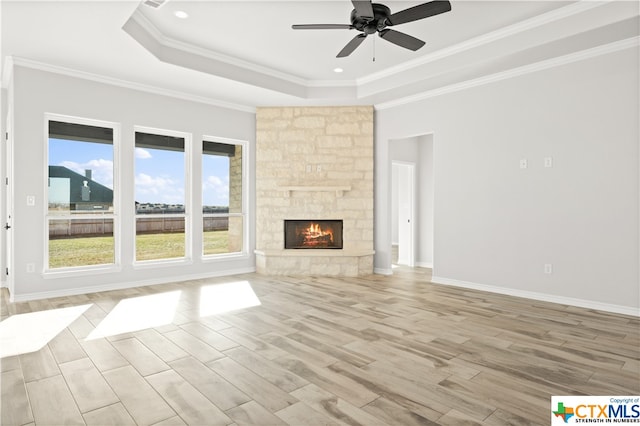 unfurnished living room featuring a stone fireplace, light hardwood / wood-style floors, a healthy amount of sunlight, and crown molding