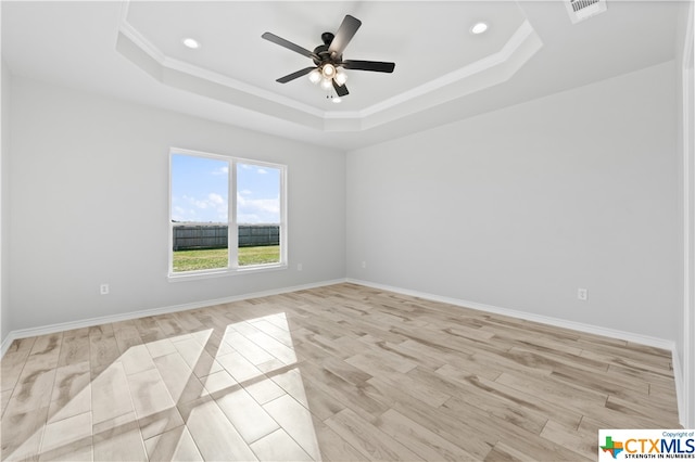 unfurnished room featuring light hardwood / wood-style floors, ceiling fan, a raised ceiling, and ornamental molding