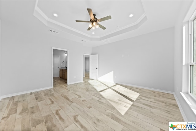 unfurnished bedroom featuring light hardwood / wood-style floors, ceiling fan, and a raised ceiling