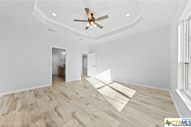 unfurnished bedroom featuring light hardwood / wood-style floors, ceiling fan, and a raised ceiling