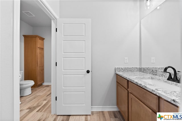 bathroom featuring toilet, vanity, and hardwood / wood-style flooring