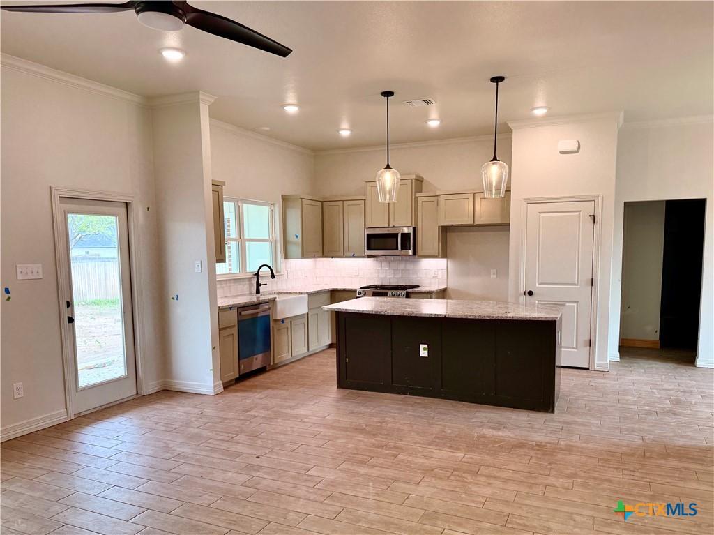 6018 Parma Ln, Temple, TX 76502 - kitchen with appliances with stainless steel finishes, a ceiling fan, a kitchen island, tasteful backsplash, and a sink
