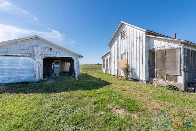 view of side of home with a garage, an outdoor structure, and a yard