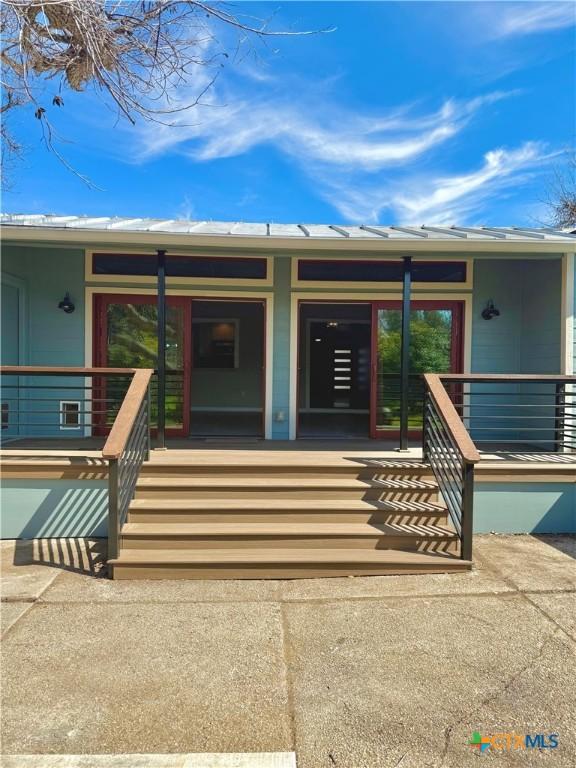 doorway to property with metal roof and a porch