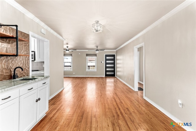 interior space with crown molding, white cabinetry, a sink, and open shelves