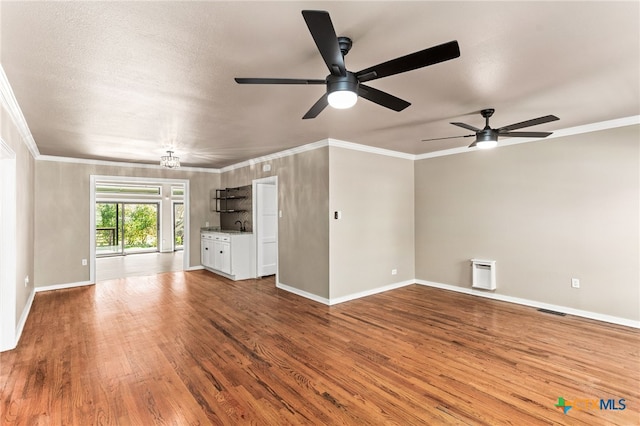 unfurnished living room featuring crown molding, baseboards, and wood finished floors