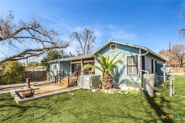 back of property featuring a gate, fence, central AC, and a yard