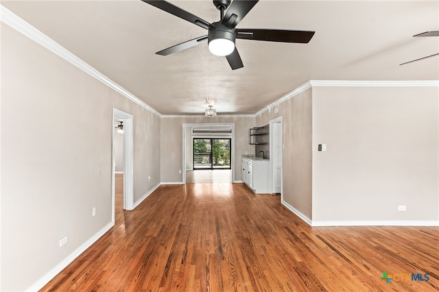 unfurnished living room with ceiling fan, ornamental molding, wood finished floors, and baseboards