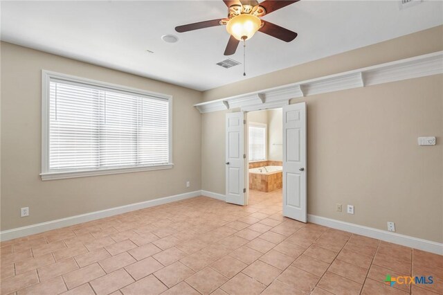 407 E Santa Rosa St, Victoria, TX 77901 - unfurnished bedroom featuring baseboards, light tile patterned flooring, connected bathroom, and ceiling fan