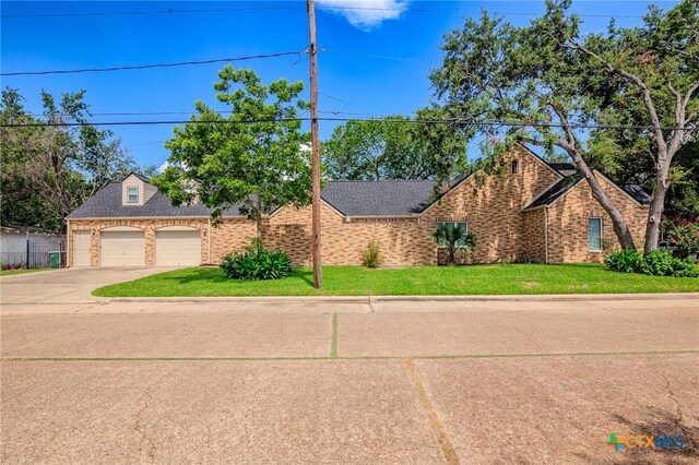 407 E Santa Rosa St, Victoria, TX 77901 - view of front of home with brick siding, driveway, a front yard, an attached garage, and a shingled roof