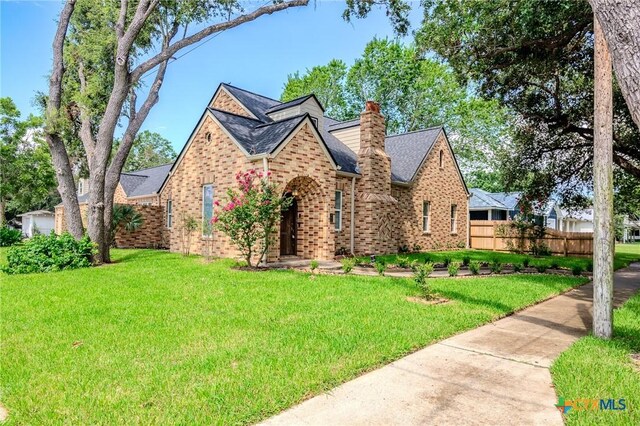 407 E Santa Rosa St, Victoria, TX 77901 - english style home with brick siding, a chimney, and a shingled roof