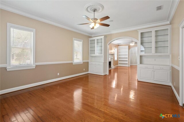 407 E Santa Rosa St, Victoria, TX 77901 - empty room featuring ceiling fan, arched walkways, ornamental molding, healthy amount of natural light, and wood finished floors